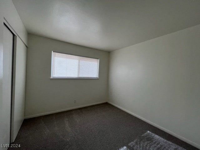 unfurnished bedroom with a closet and dark carpet