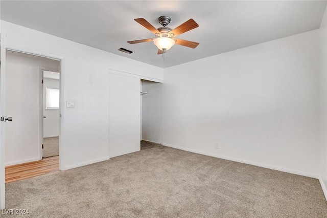 unfurnished bedroom featuring light carpet, a closet, and ceiling fan