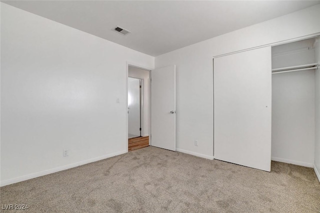 unfurnished bedroom with light carpet and a closet