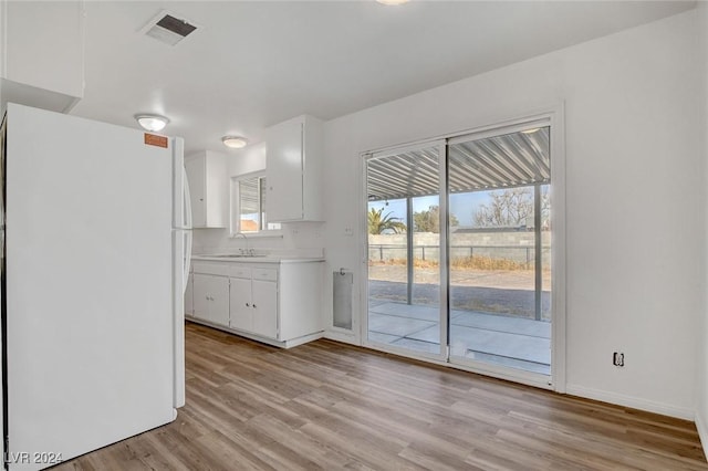 kitchen featuring white fridge, sink, white cabinets, and light hardwood / wood-style floors