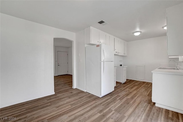 kitchen featuring white cabinetry, sink, white fridge, and light hardwood / wood-style flooring