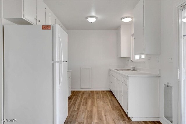 kitchen with white cabinetry, sink, white fridge, and light hardwood / wood-style flooring