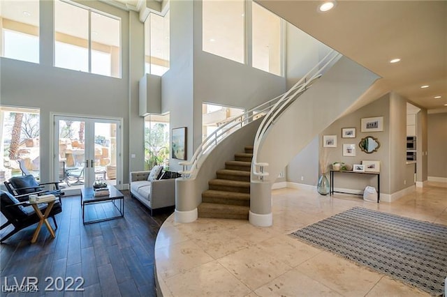 foyer featuring wood-type flooring, a high ceiling, and french doors