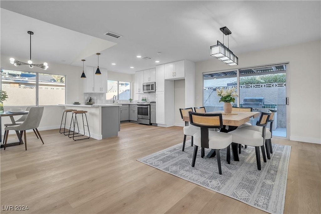 dining area featuring sink, a notable chandelier, and light wood-type flooring