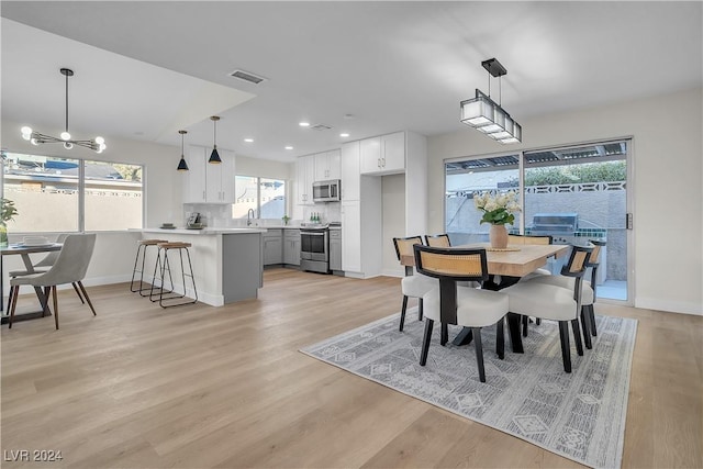 dining area featuring sink, a notable chandelier, and light wood-type flooring