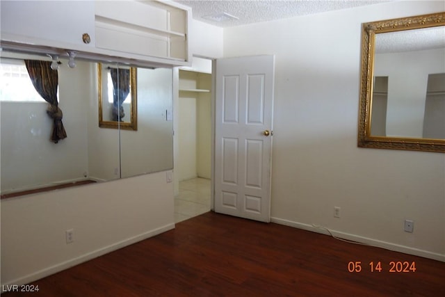 unfurnished bedroom featuring a textured ceiling and dark wood-type flooring