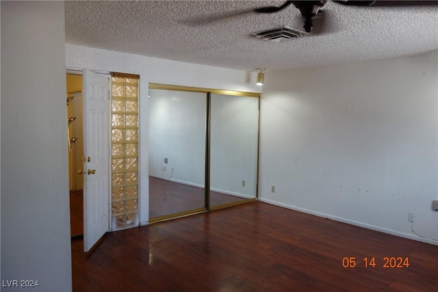 unfurnished bedroom featuring a textured ceiling, a closet, and dark hardwood / wood-style floors