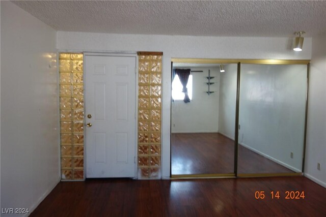 interior space featuring a textured ceiling, dark hardwood / wood-style flooring, and a closet