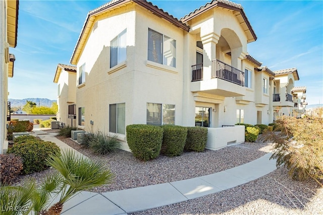 view of home's exterior featuring a mountain view, a balcony, and central AC