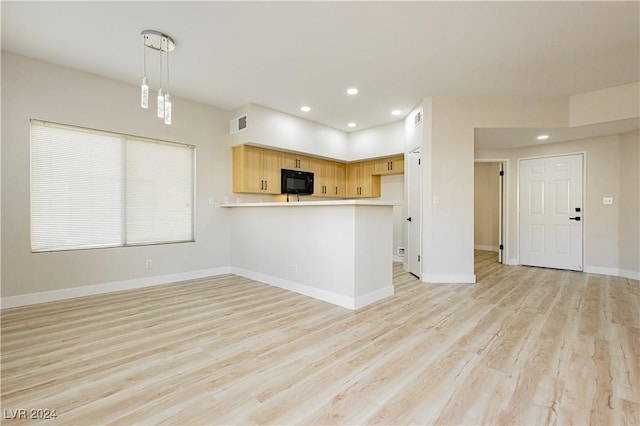 kitchen featuring kitchen peninsula, light brown cabinets, light wood-type flooring, and hanging light fixtures