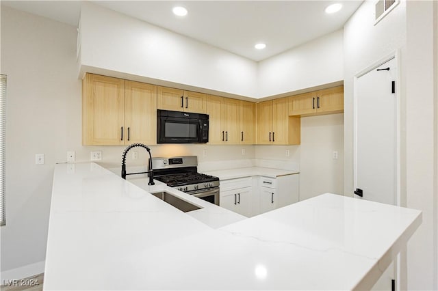 kitchen featuring stainless steel gas stove, white cabinetry, kitchen peninsula, and light brown cabinetry