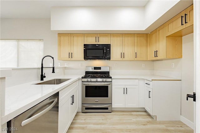 kitchen with sink, light hardwood / wood-style floors, light stone counters, white cabinetry, and stainless steel appliances