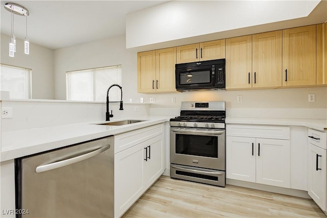 kitchen with hanging light fixtures, sink, light hardwood / wood-style floors, and appliances with stainless steel finishes