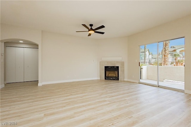 unfurnished living room with a tile fireplace, ceiling fan, and light hardwood / wood-style floors