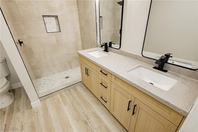 bathroom featuring tiled shower, vanity, hardwood / wood-style flooring, and toilet