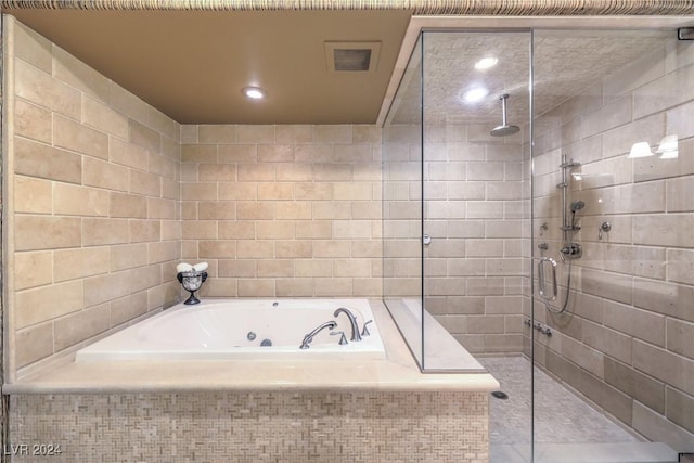 bathroom featuring tile walls and independent shower and bath