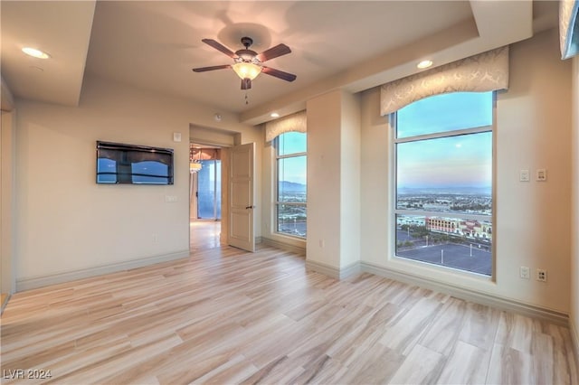 spare room featuring ceiling fan, a wealth of natural light, and light hardwood / wood-style flooring