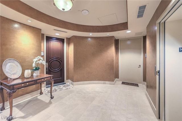 hallway featuring light tile patterned floors and a tray ceiling