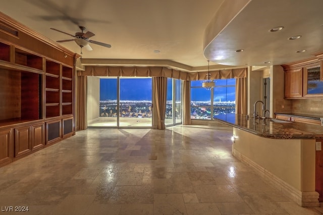 unfurnished living room featuring sink, ceiling fan, and built in shelves