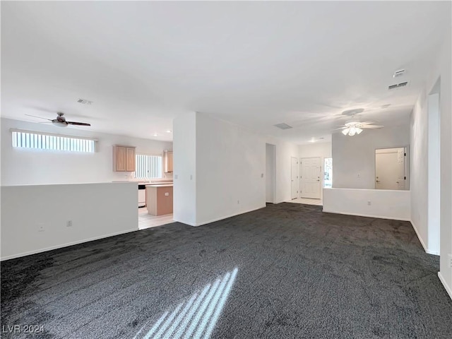 unfurnished living room with ceiling fan and dark carpet