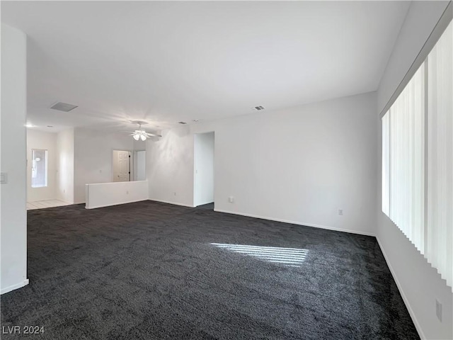 unfurnished living room with ceiling fan and dark colored carpet