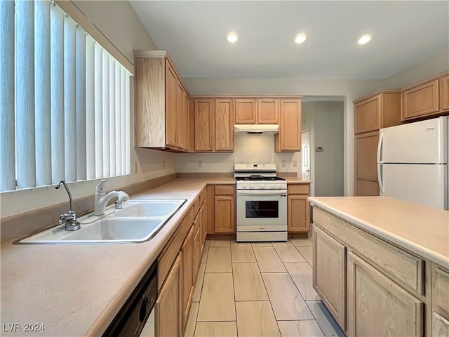 kitchen with light brown cabinets, white appliances, and sink