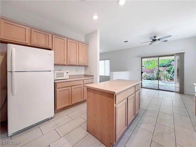 kitchen featuring light brown cabinetry, white appliances, a kitchen island, and ceiling fan