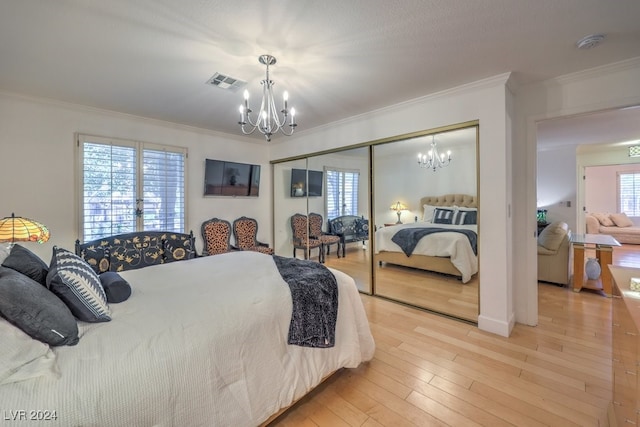 bedroom with hardwood / wood-style floors, a notable chandelier, crown molding, and a closet