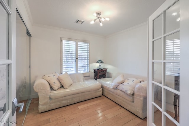 living room with light wood-type flooring, ornamental molding, and a chandelier