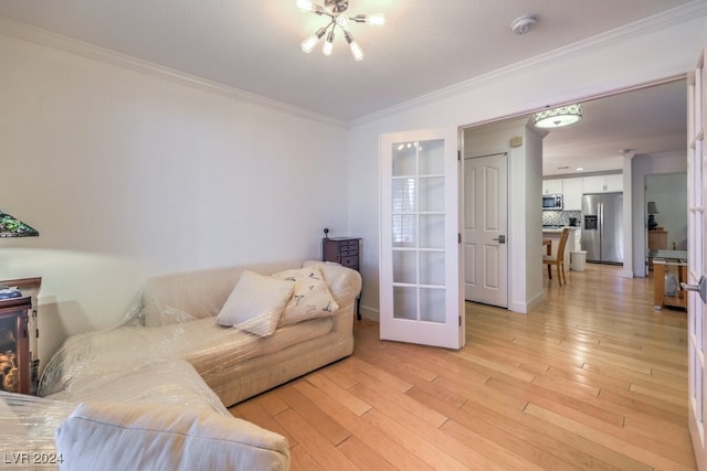 living room with crown molding, an inviting chandelier, and light wood-type flooring