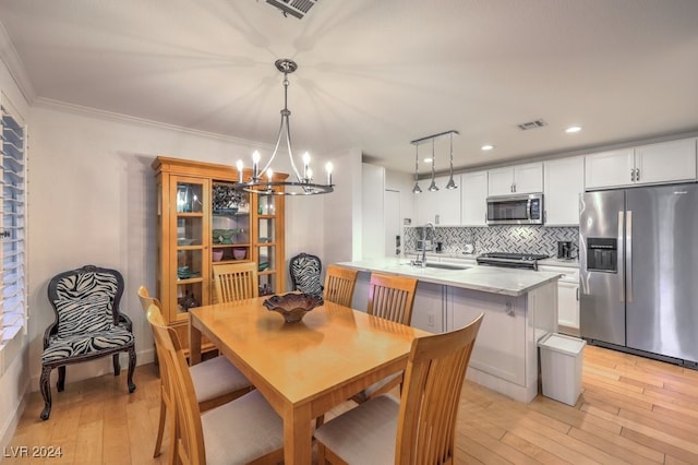 dining room with crown molding, light hardwood / wood-style flooring, sink, and a notable chandelier