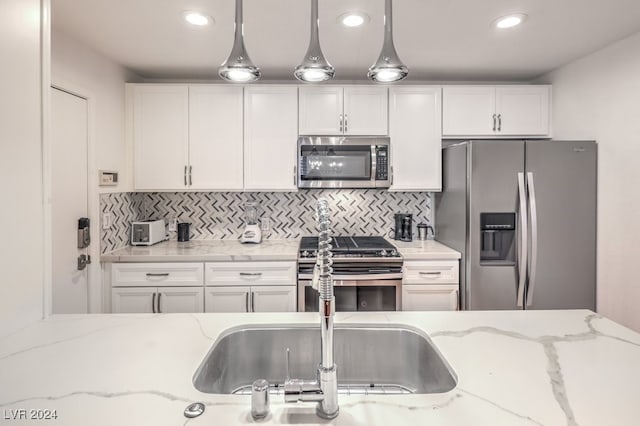 kitchen featuring backsplash, light stone countertops, pendant lighting, and stainless steel appliances