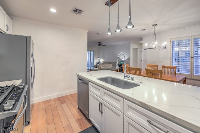 kitchen featuring ceiling fan with notable chandelier, stainless steel appliances, sink, light hardwood / wood-style floors, and white cabinetry