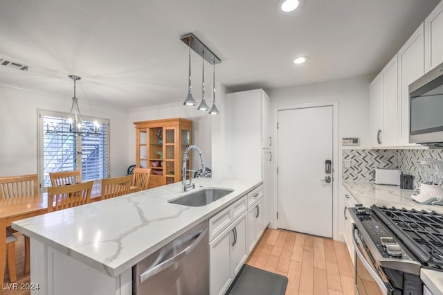 kitchen featuring stainless steel appliances, sink, decorative light fixtures, an inviting chandelier, and white cabinets