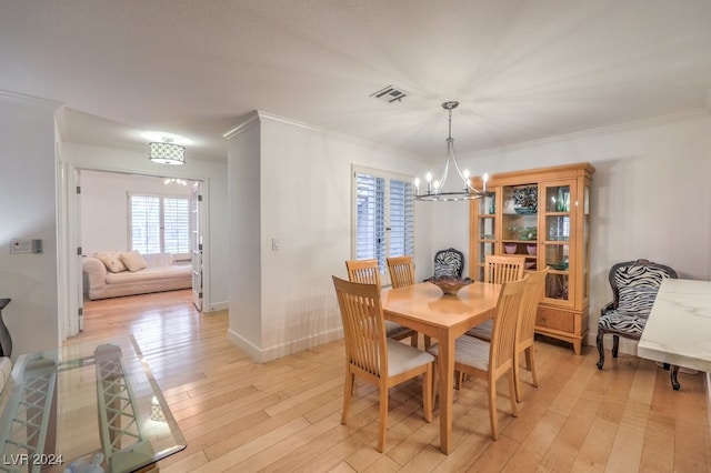 dining area with an inviting chandelier, ornamental molding, and light wood-type flooring