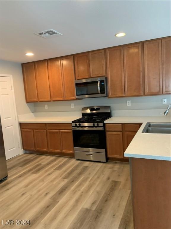 kitchen featuring light wood-type flooring, stainless steel appliances, and sink