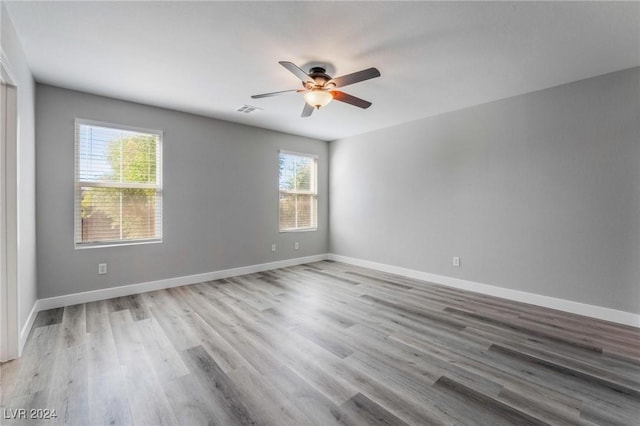 spare room featuring ceiling fan, a healthy amount of sunlight, and light hardwood / wood-style flooring