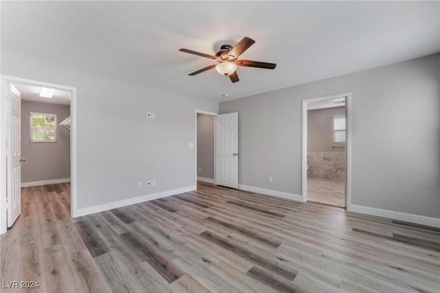 unfurnished bedroom with ceiling fan, a spacious closet, connected bathroom, light hardwood / wood-style floors, and a closet