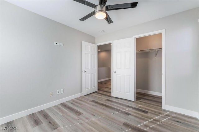 unfurnished bedroom with ceiling fan, a walk in closet, light wood-type flooring, and a closet