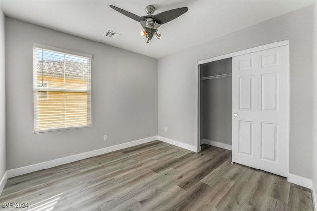 unfurnished bedroom featuring ceiling fan, a closet, and hardwood / wood-style flooring