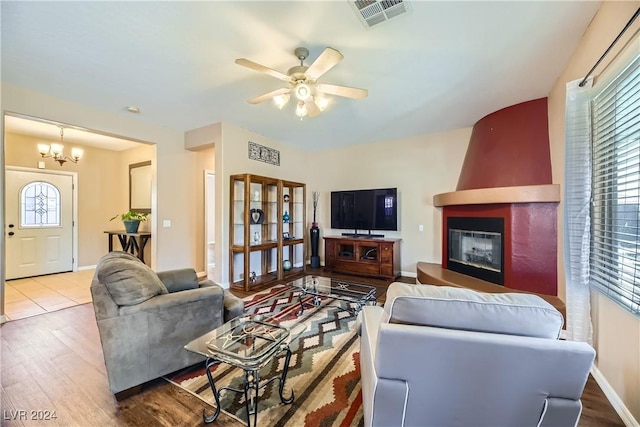 living room featuring hardwood / wood-style floors, ceiling fan with notable chandelier, and a fireplace