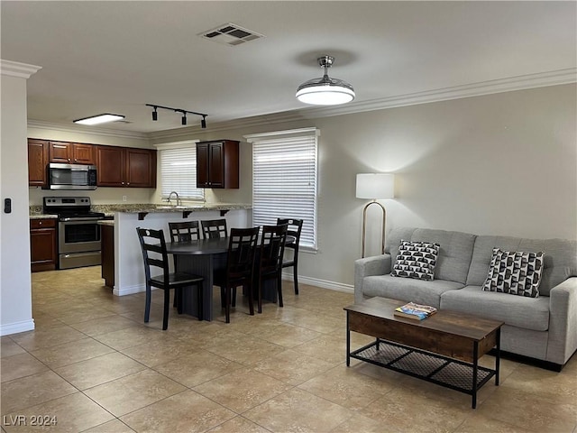 dining space featuring ornamental molding, sink, and light tile patterned floors