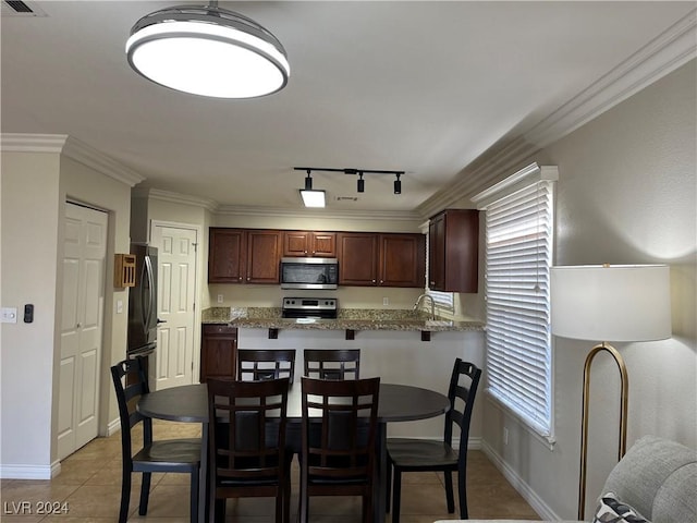 kitchen featuring kitchen peninsula, track lighting, stainless steel appliances, crown molding, and light tile patterned flooring