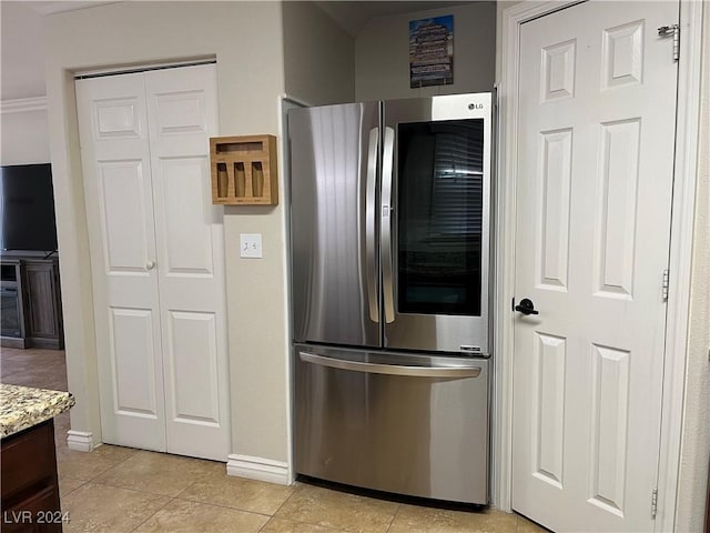 kitchen with stainless steel fridge, light tile patterned floors, light stone countertops, and ornamental molding