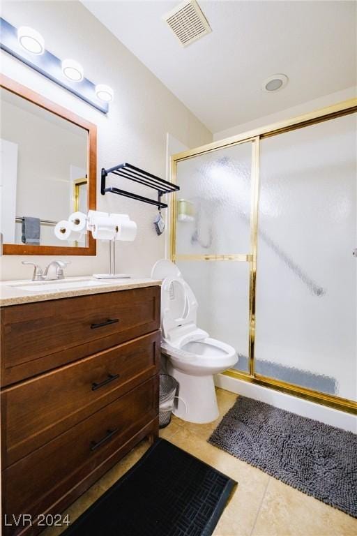 bathroom featuring tile patterned floors, vanity, toilet, and a shower with door