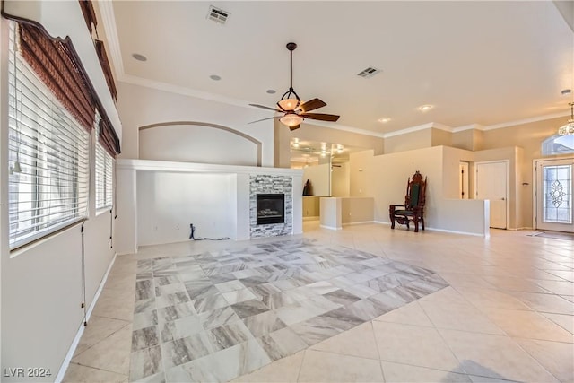 unfurnished living room featuring ceiling fan, a stone fireplace, light tile patterned floors, and crown molding