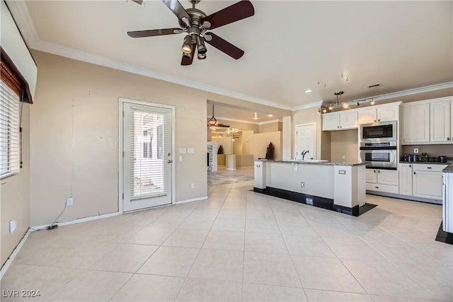 kitchen with ornamental molding, stainless steel appliances, a kitchen island with sink, ceiling fan, and white cabinets