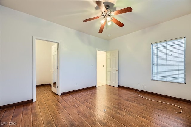 unfurnished bedroom featuring a walk in closet, dark hardwood / wood-style floors, and ceiling fan