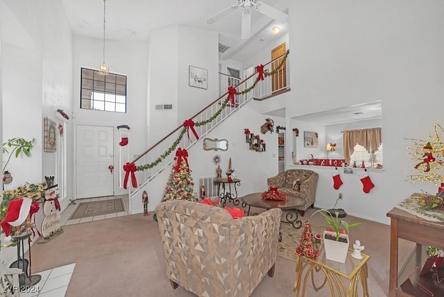 living room featuring ceiling fan, a towering ceiling, and light colored carpet