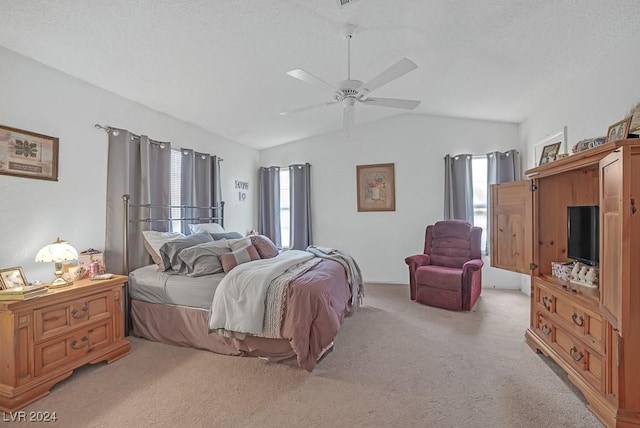 bedroom with a textured ceiling, light colored carpet, vaulted ceiling, and ceiling fan